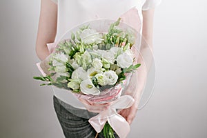 Florist at work. Make bouquet of white lisiantus . Vintage floristic background, colorful roses, antique scissors and a