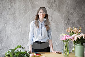 Florist at work: pretty young woman making fashion modern bouquet of different flowers