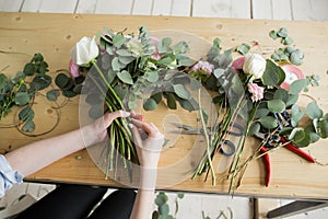 Florist at work: pretty young woman making fashion modern bouquet of different flowers