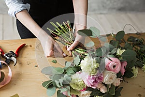 Florist at work: pretty young woman making fashion modern bouquet of different flowers