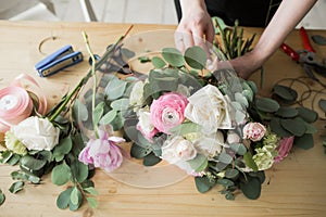 Florist at work: pretty young woman making fashion modern bouquet of different flowers