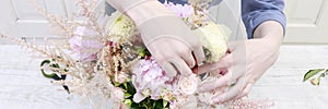 Woman arranging bouquet with pink peonies, roses and yellow dahlias