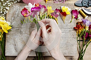 Florist at work. Woman making bouquet of freesia flowers