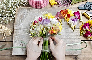 Florist at work. Woman making bouquet of freesia flowers photo