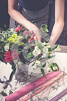 Florist works. Women`s hands making a wedding bouquet of roses. Small business concept. Vertical shot