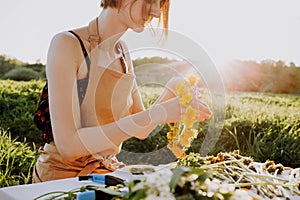 Florist workshop. Pretty woman making wreath from dandelions. Romantic background of florist at work