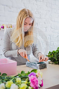 Florist wraps oasis floral foam in cling film for flower arrangement at shop