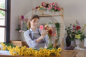Floristry concept, Woman florist arranged colorful gerberas in glass vase for client at flower shop