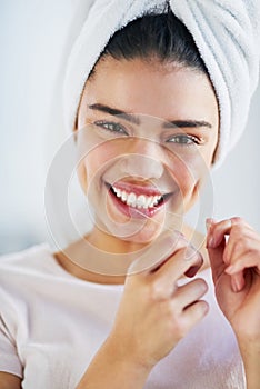 Floss as much as you brush. Portrait of a beautiful young woman flossing her teeth in the bathroom at home.