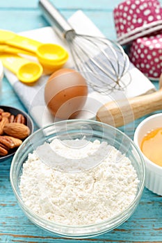 Flour with baking ingredients on wood background