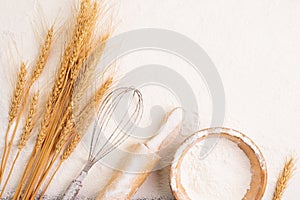 Flour in bowl and wheat grains with wheat ears, barley, cooking, bread, and cookies, arranged on the table in a rustic kitchen,