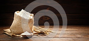 Flour in burlap bag on a wooden background.