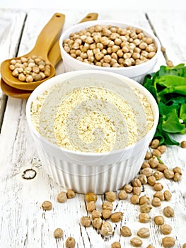 Flour chickpeas in white bowl with peas on light board