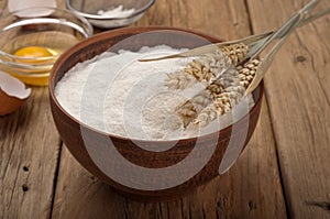 Flour in a clay bowl with ears of wheat