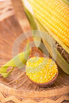 Flour corn in a spoon on the dark wooden boards