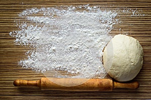 Flour, dough and rolling pin on a wooden table