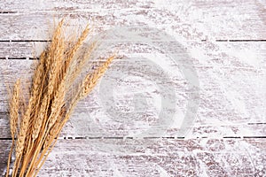 Flour and ears of wheat, barley, cooking, bread, and cookies were arranged on the wooden table background in a rustic kitchen. Top