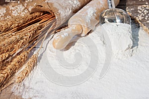 Flour and ears of wheat, barley, cooking, bread, and cookies were arranged on the wooden table background in a rustic kitchen. Top