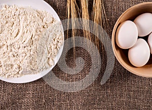 Flour, eggs in a basket and wheat ears. Baking background.