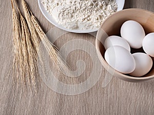 Flour, eggs in a basket and wheat ears. Baking background.