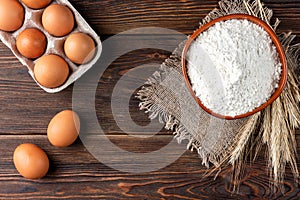 Flour and eggs on dark wooden table. Baking background