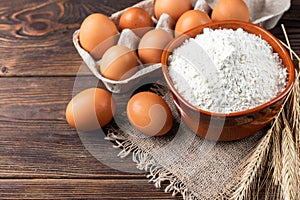 Flour and eggs on dark wooden table. Baking background