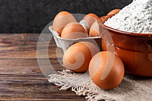 Flour and eggs on dark wooden table. Baking background