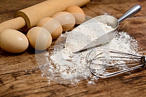 Flour, eggs and rolling pin on wooden table