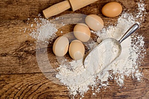 Flour, eggs and rolling pin on wooden table