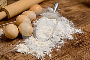 Flour, eggs and rolling pin on wooden table