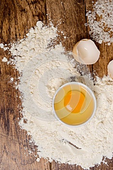 Flour, eggs, salt, towel, rolling pin on wooden table ready for cooking