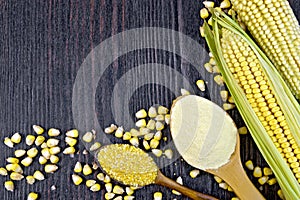 Flour and grits corn in spoons on dark wooden board