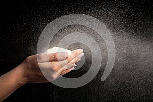 Flour in hands blowing on black background like snow