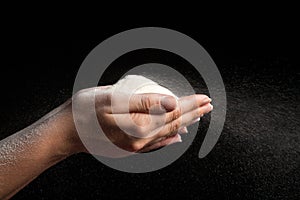 Flour in hands blowing on black background like snow