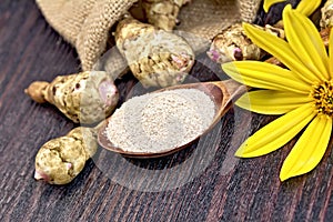 Flour of Jerusalem artichoke in spoon with vegetable on board