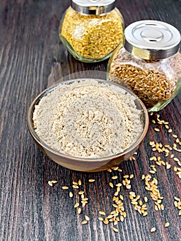 Flour linen in bowl with seeds in jars on wooden board