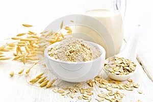 Flour oat in bowl with milk on light wooden board