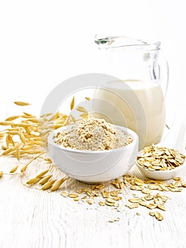 Flour oat in bowl with milk on wooden board