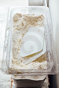 Flour in plastic box with plastic scrapper for making bread