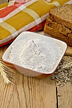 Flour rye in a bowl with bread and ears rye