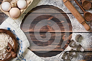 Flour scattered in the form of a circle, rolling pin and white linen napkin on an old wooden background. Place for text.