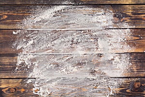 Flour scattered in the form of a circle, rolling pin and white linen napkin on an old wooden background. Place for text.