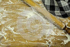 Flour scattered on the kitchen board, rolling pin and a black and white towel