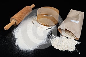 Flour sieved for homemade pastries. Accessories in home kitchen on a dark table