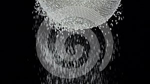 Flour sift through sieve on black background. Slow motion, closeup