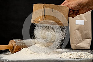 Flour sifted through an old wooden sieve. Accessories in home kitchen on a dark table