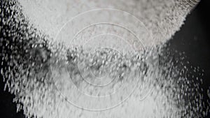 Flour is sifted through a sieve on black background