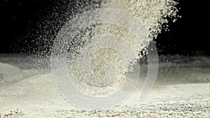 The flour is sifted through a sieve. On a black background. Filmed on a high-speed camera at 1000 fps.