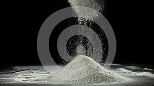 The flour is sifted through a sieve. On a black background. Filmed on a high-speed camera at 1000 fps.