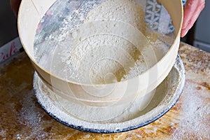 Flour is sifted through a wooden sieve